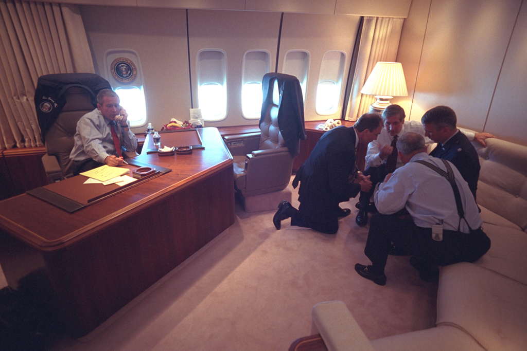 President George W. Bush talks on the telephone, September 11, 2001, as senior staff huddle aboard Air Force One. (P7079-10)