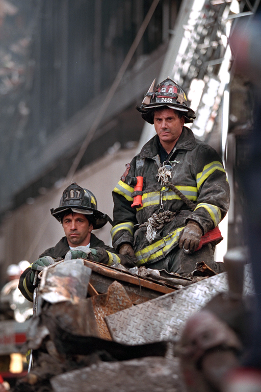 Two firefighters listen to President George W. Bush, September 14, 2001, during his visit to New York City and the site of the terrorist attacks on the World Trade Center. (P7377-06)