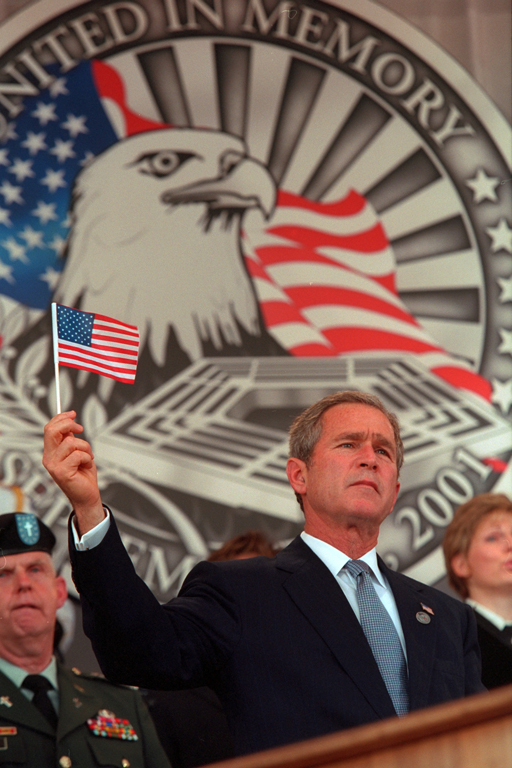 President George W. Bush holds up a small American flag, October 11, 2001, during the Department of Defense Service of Remembrance for those who lost their lives at the Pentagon on September 11th in Arlington, Virginia. (P8416-16)