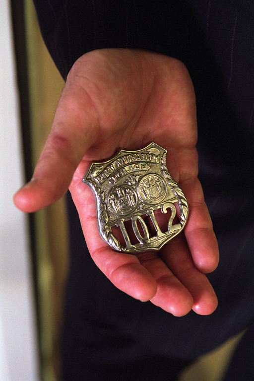 Standing in the Oval Office, October 15, 2001, President George W. Bush holds the badge of a police officer killed in the September attacks. (P8576-12a)