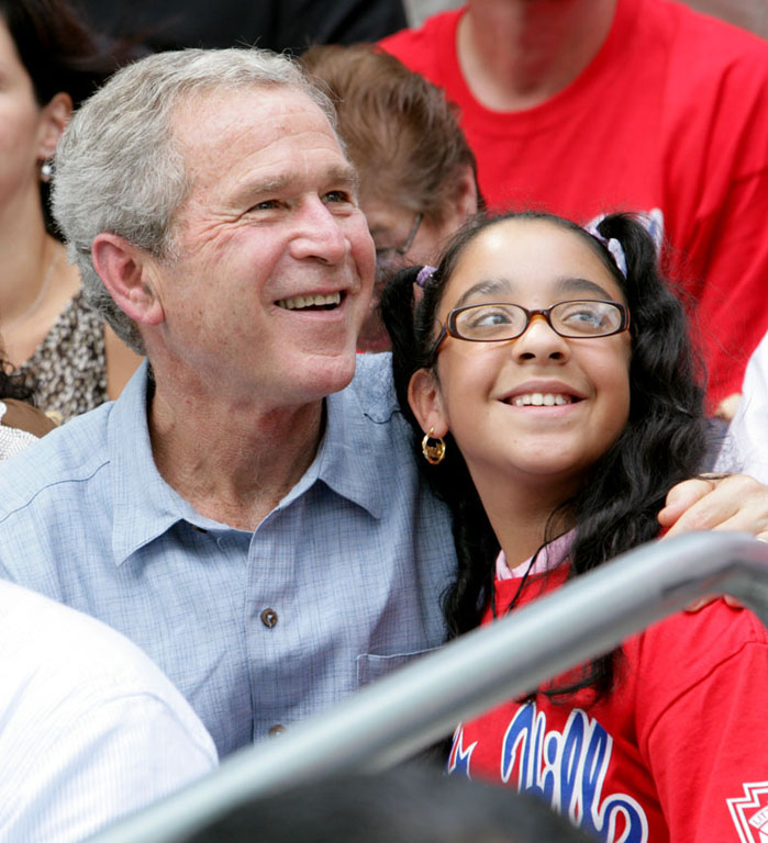 President George W. Bush poses for a photo with a fan in the stands