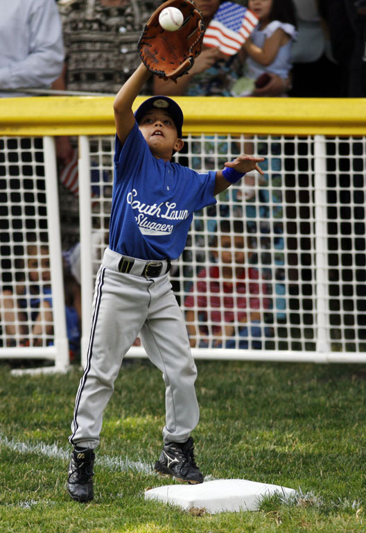 The first base player catches a ball in his glove.