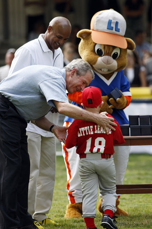 President George W. Bush presents Angel Tavarez with a baseball. President Bush is joined on the field by Roberto Clemente, Jr. and Dugout, the Little League mascot.