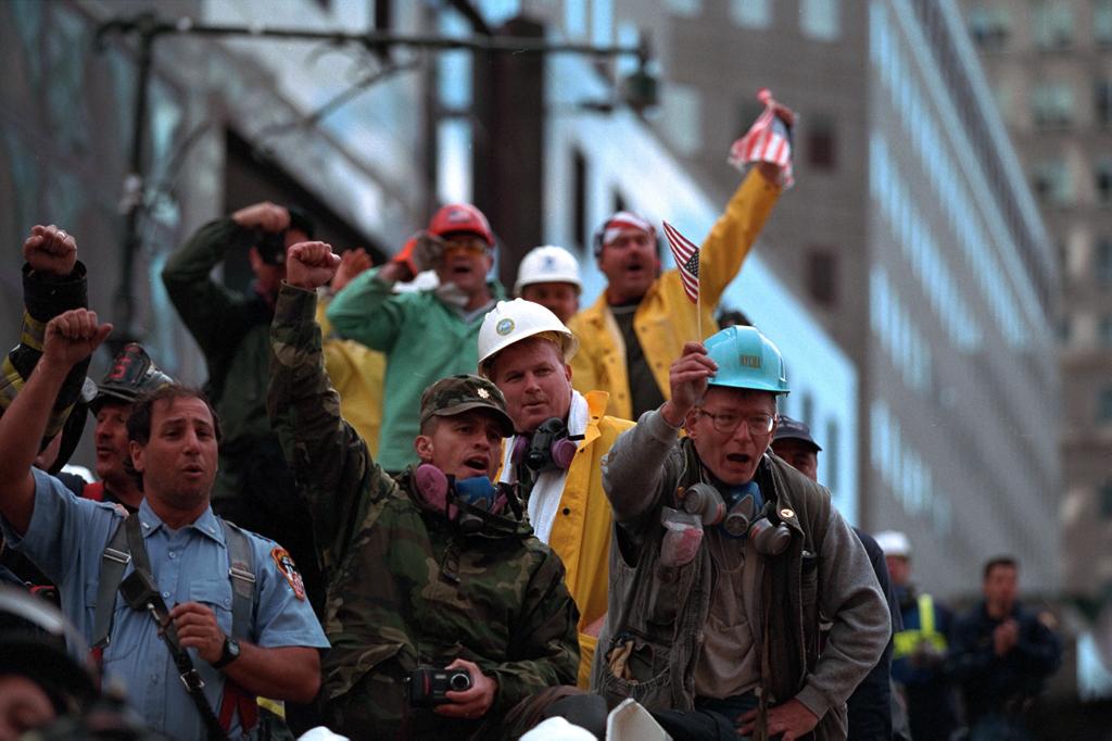 Rescue workers cheer, chant, and wave American flags as President Bush visits Ground Zero.
