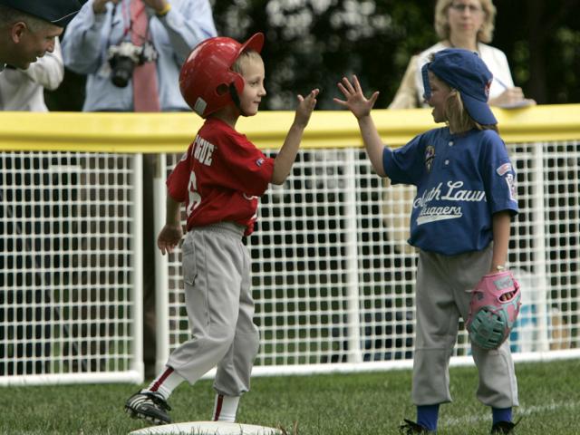 Two opposing players high-five on the field