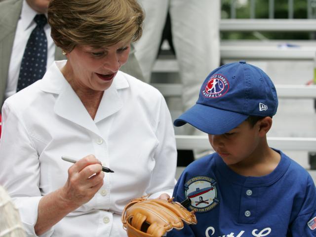 Mrs. Laura W. Bush autographs a glove for a Dolcom Little League Indian.