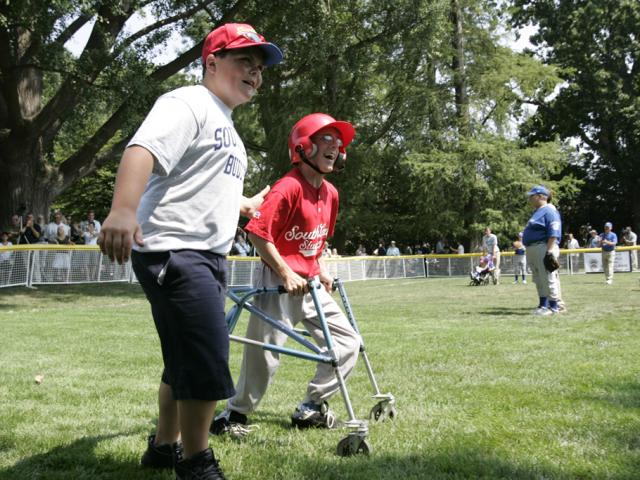 A player is accompanied to first base by a South Lawn buddy.