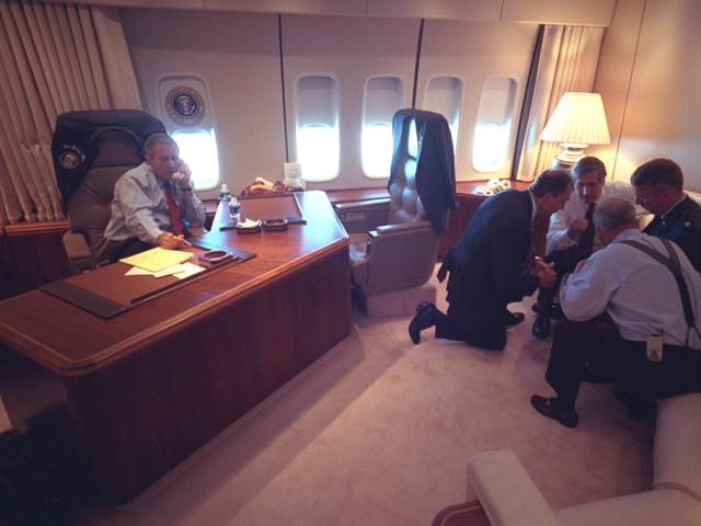 President George W. Bush talks on the telephone, September 11, 2001, as senior staff huddle aboard Air Force One. (P7079-10)