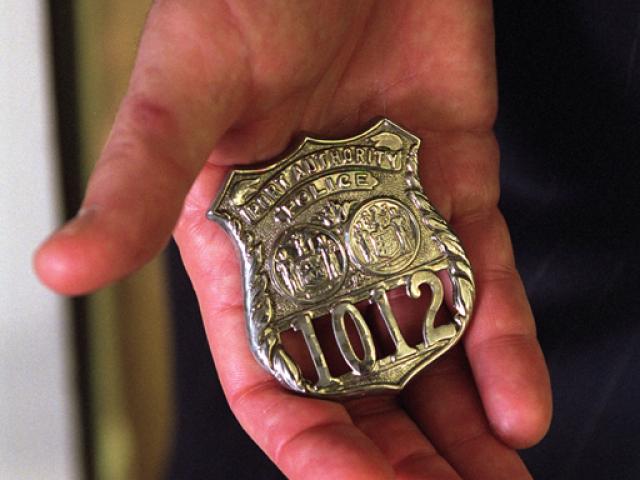 Standing in the Oval Office, October 15, 2001, President George W. Bush holds the badge of a police officer killed in the September attacks. (P8576-12a)