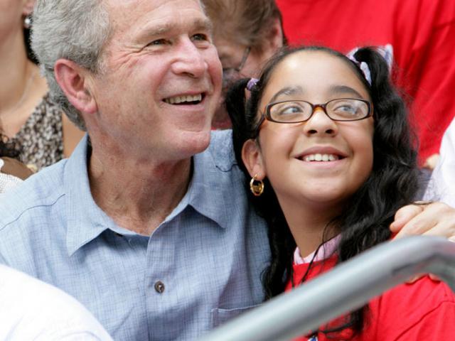 President George W. Bush poses for a photo with a fan in the stands