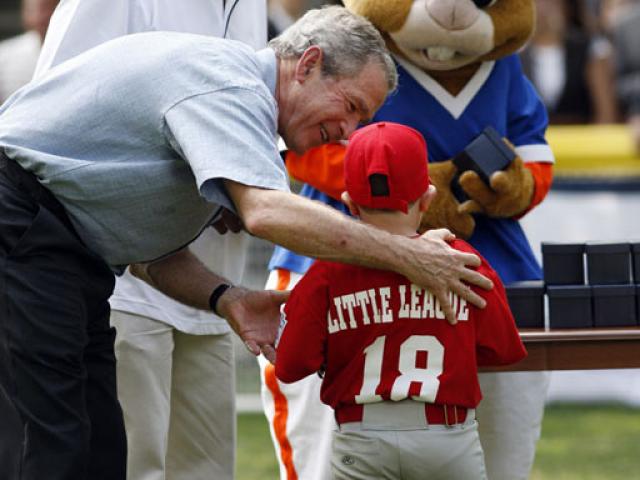 President George W. Bush presents Angel Tavarez with a baseball. President Bush is joined on the field by Roberto Clemente, Jr. and Dugout, the Little League mascot.