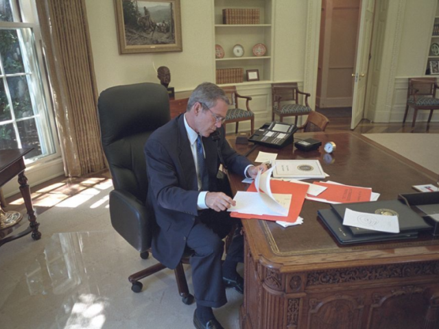 President George W. Bush reviews documents in the Oval Office