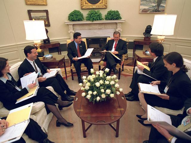 President George W. Bush sits with staff in Oval Office 