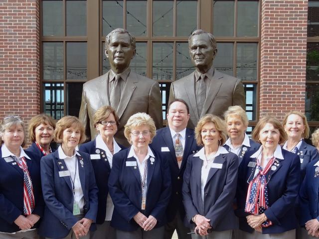 Docents stand in front of the statues of President George W. Bush and President George H.W. Bush.