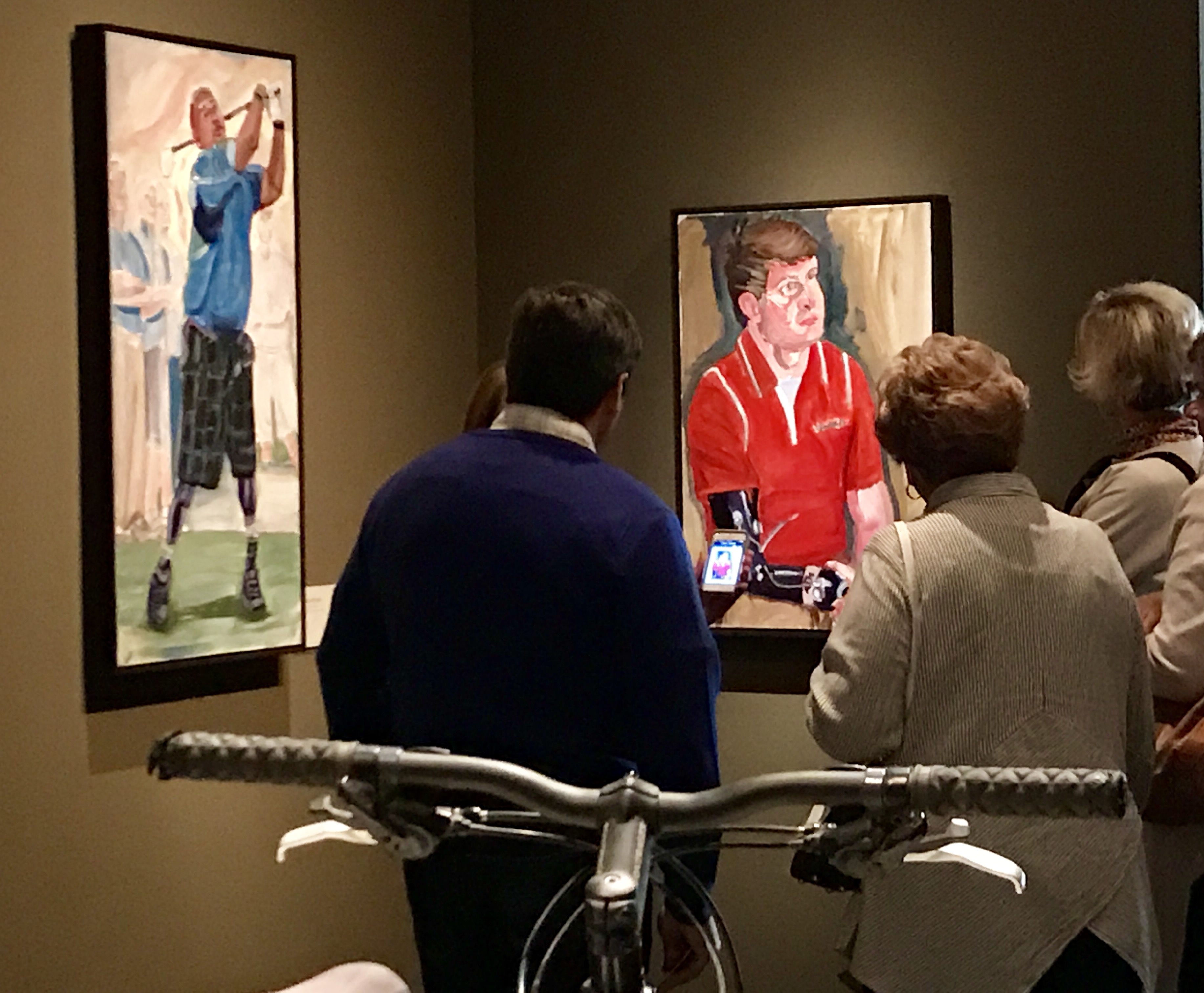A photo of visitors looking at paintings of various athletes, from the 2017 exhibit Portraits of Courage, at the George W Bush Library and Museum 