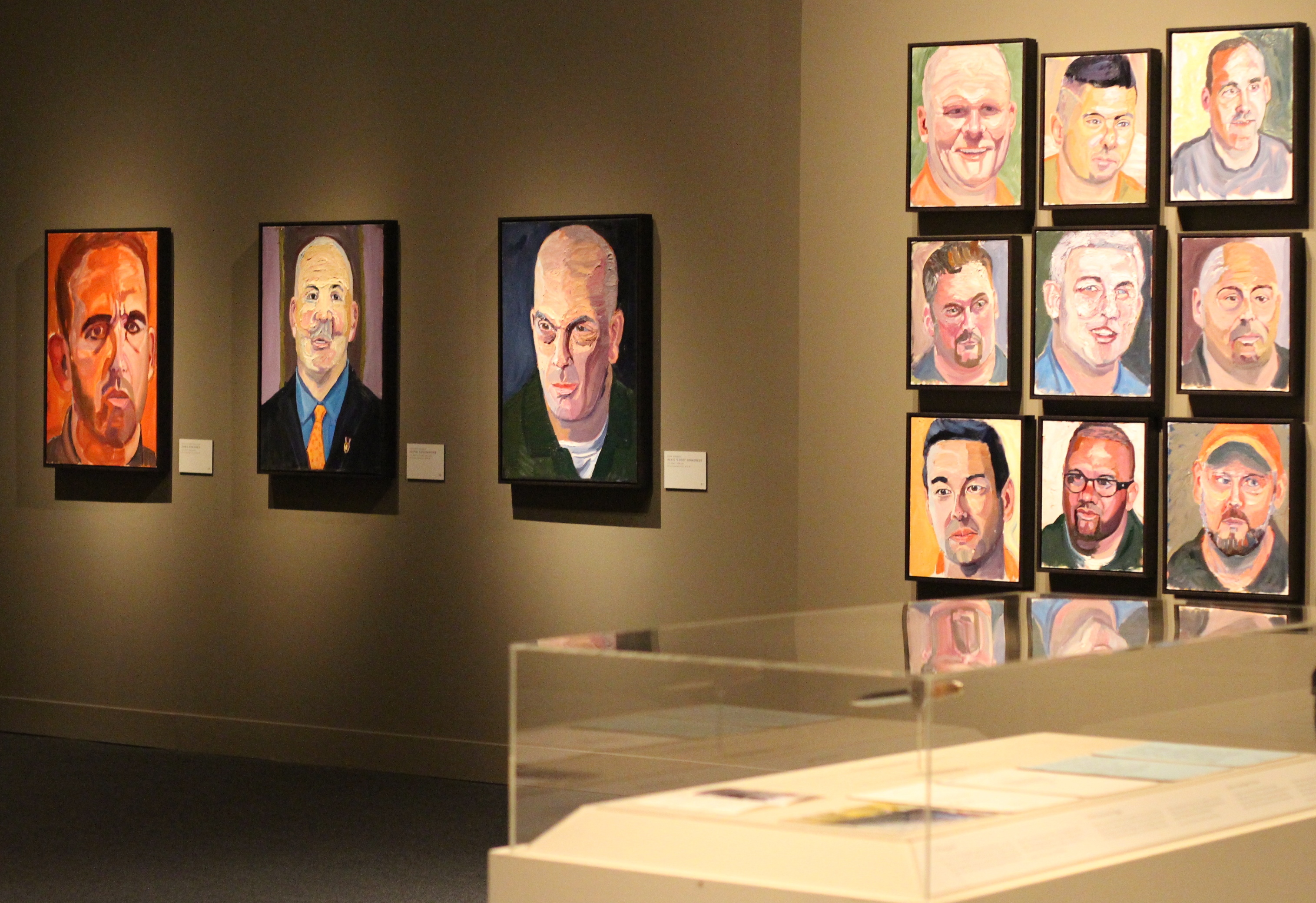 A photo of portraits hanging on the walls near an exhibit, part of the 2017 Portraits of Courage exhibit at the George W Bush Museum.