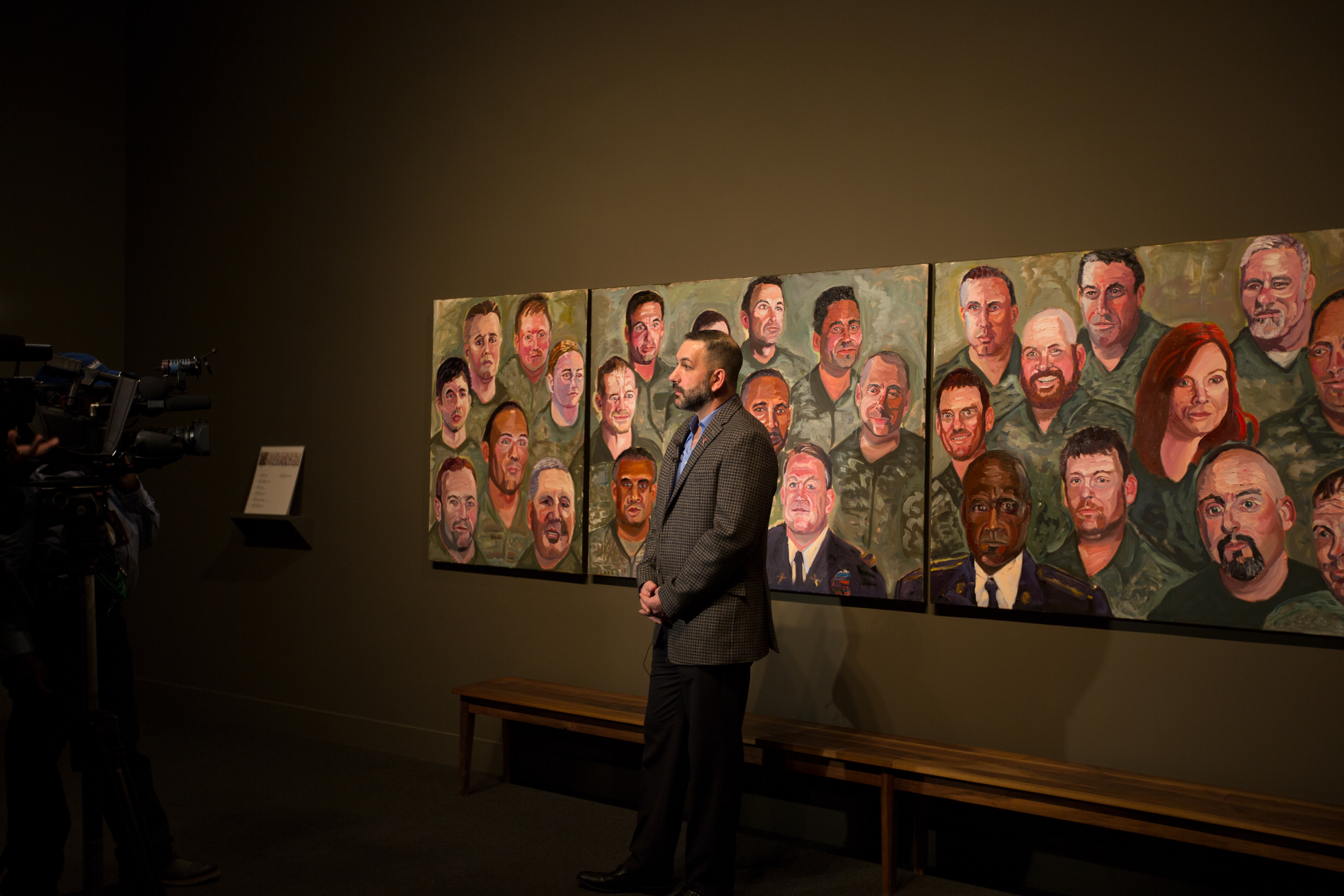 A photo of a man being interviewed while standing near his portrait panel, painted by President George W Bush, part of the 2017 exhibit Portraits of Courage, at the George W Bush Library and Museum