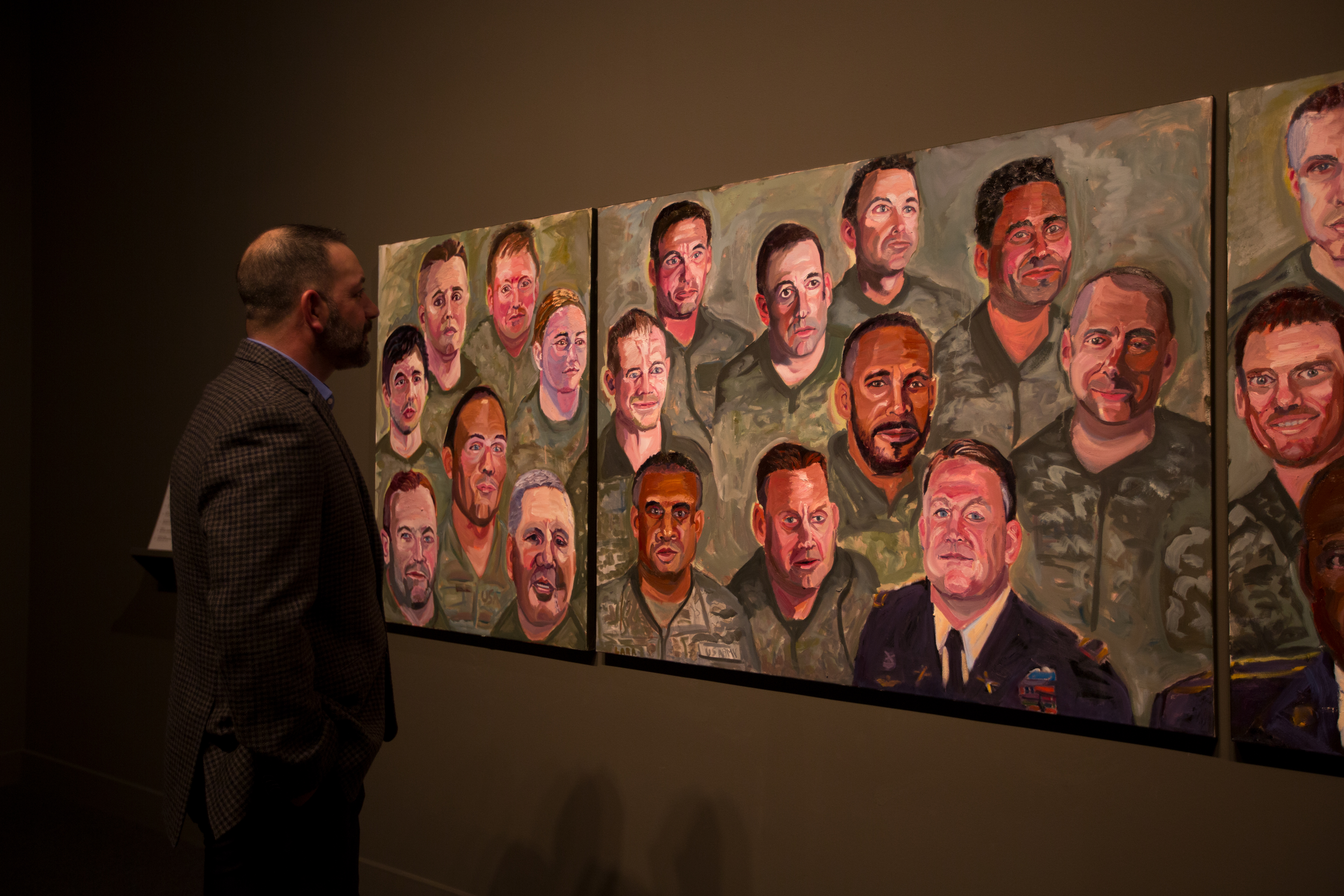 A photo of a man looking at his portrait in a mural painted by President Bush, part of the 2017 Portraits of Courage exhibit at the George W Bush Library and Museum.