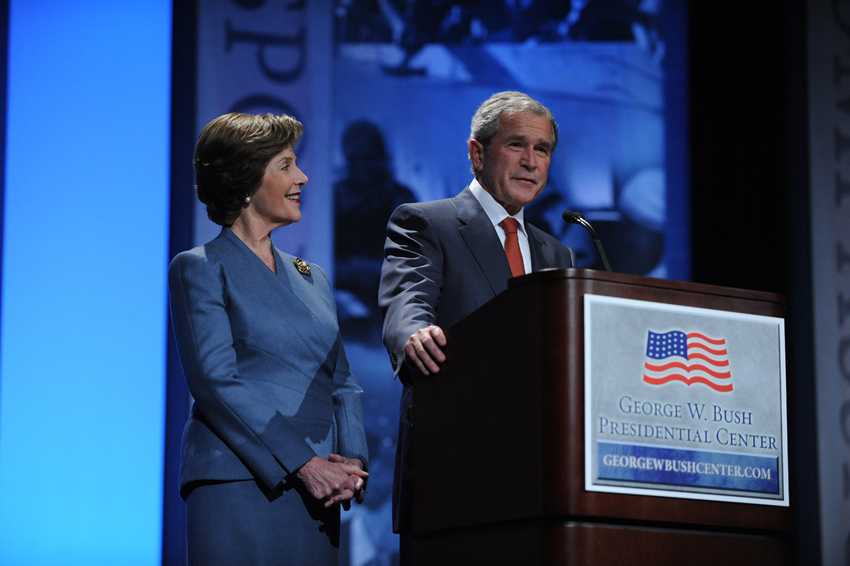 Woman and man standing in front of mic and podium