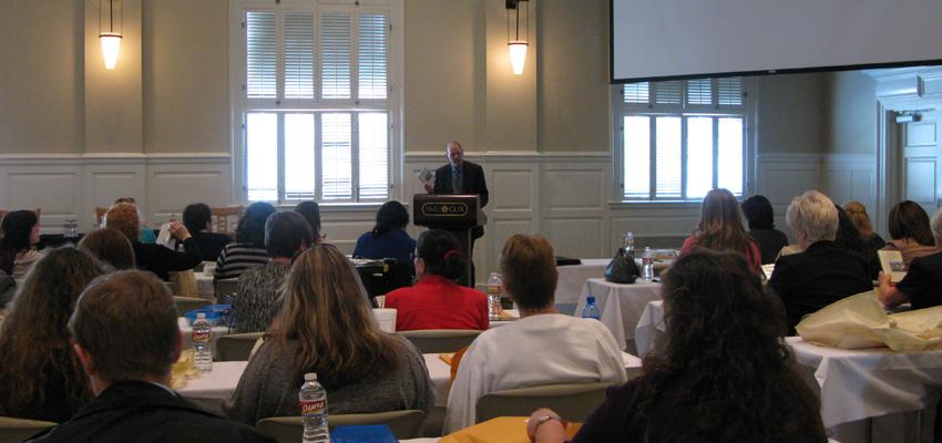 John Riley speaks at a podium in front of teachers