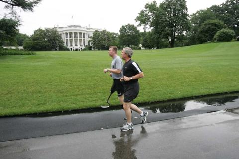 President George W. Bush runs with U.S. Army Staff Sergeant Christian Bagge of Oregon, on the South Lawn, June 27, 2006. President Bush met Sgt. Bagge at Brooke Army Medical Center January 1, 2006, where he promised to run with Sgt. Bagge.