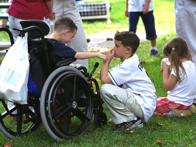 Three children gather to watch tee ball on the South Lawn.