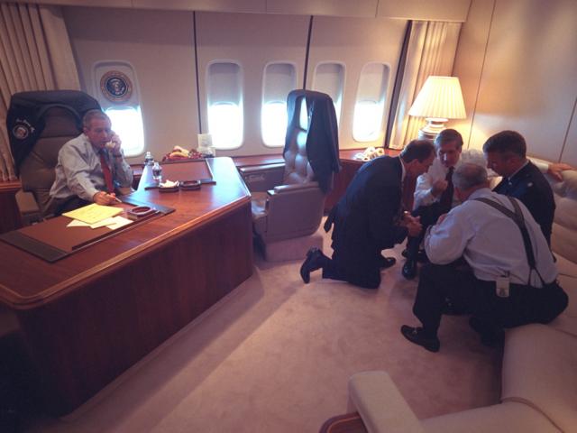 President George W. Bush talks on the telephone, September 11, 2001, as senior staff huddle aboard Air Force One. (P7079-10)