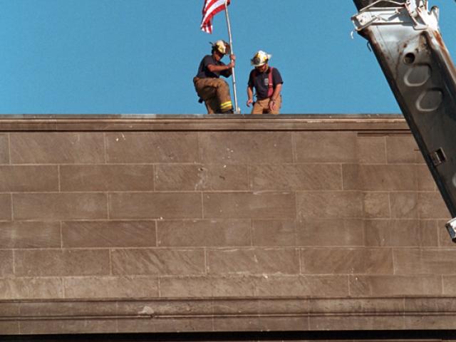 Echoing the actions of the soldiers who raised the flag in victory at Iwo Jima during World War II, firefighters post the American flag directly into the scarred stone of the Pentagon, September 12, 2001, in Arlington, Virginia. (P7244-22)