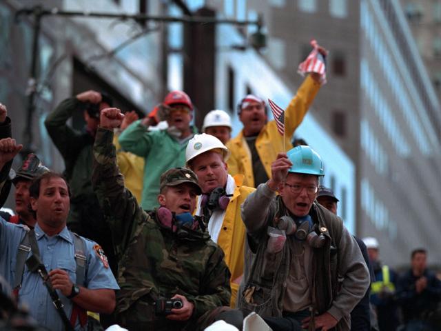 Rescue workers cheer, chant, and wave American flags as President Bush visits Ground Zero.