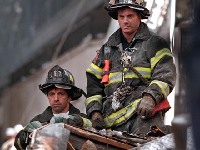 Two firefighters listen to President George W. Bush, September 14, 2001, during his visit to New York City and the site of the terrorist attacks on the World Trade Center. (P7377-06)