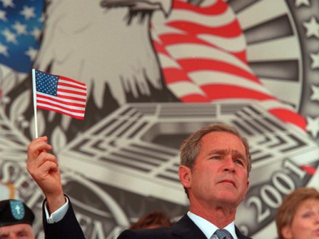 President George W. Bush holds up a small American flag, October 11, 2001, during the Department of Defense Service of Remembrance for those who lost their lives at the Pentagon on September 11th in Arlington, Virginia. (P8416-16)