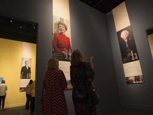 An image of visitors looking at photos of Nancy Reagan and Barbara Bush in the 2018 First Ladies exhibit at the George W Bush Library and Museum