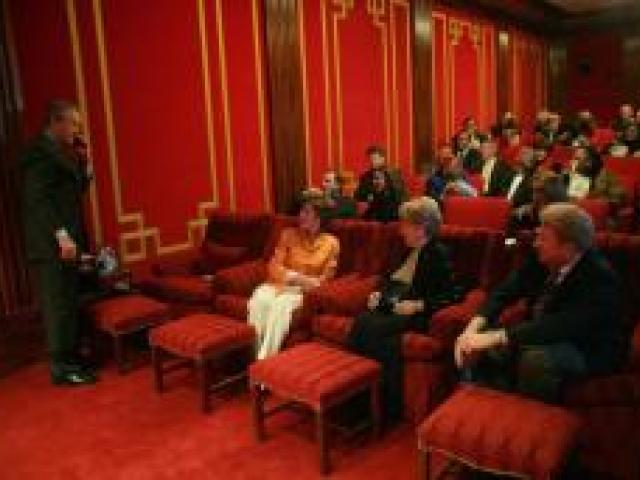 President George W. Bush talks on the phone in the White House Family Theatre February 22, 2006, as guests settle in for a screening of the movie “Glory Road.”
