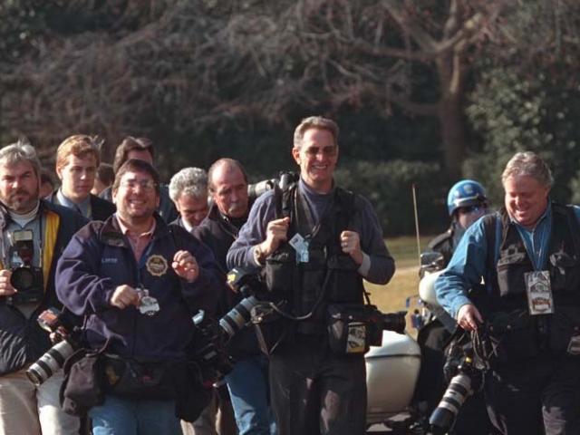 Members of the press walk next to each other on White House grounds