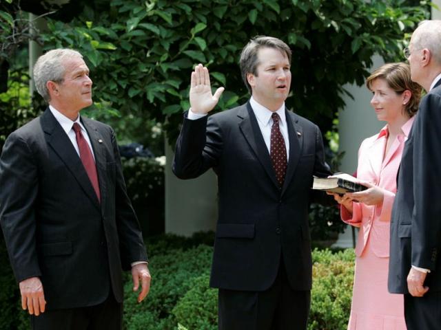 President George W. Bush looks on as Justice Anthony Kennedy swears in Brett Kavanaugh to the U.S. Court of Appeals for the District of Columbia during a ceremony, June 1, 2006, in the Rose Garden.