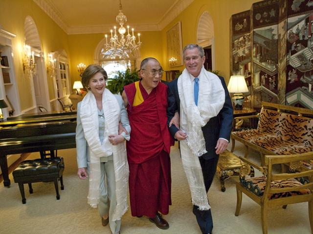 Wearing the traditional white Tibetan scarves presented to them upon his greeting, President George W. Bush and Mrs. Laura Bush walk with the Dalai Lama through the Center Hall of the Private Residence at the White House.