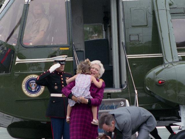 President and Mrs. Bush disembark from Marine One and are greeted by their granddaughter, Ellie LeBlond, and their dogs, Millie and Ranger, August 10, 1990. George Bush Presidential Library and Museum. P15074-22.