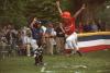 A tee ball player leaps in the air as he crosses home.