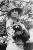 Mrs. Calvin Coolidge, half-length portrait, standing, facing front, holding her pet raccoon. Photograph taken between 1921 and 1923.