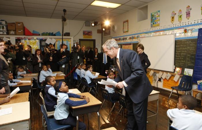 President George W. Bush stands in a classroom with students and press