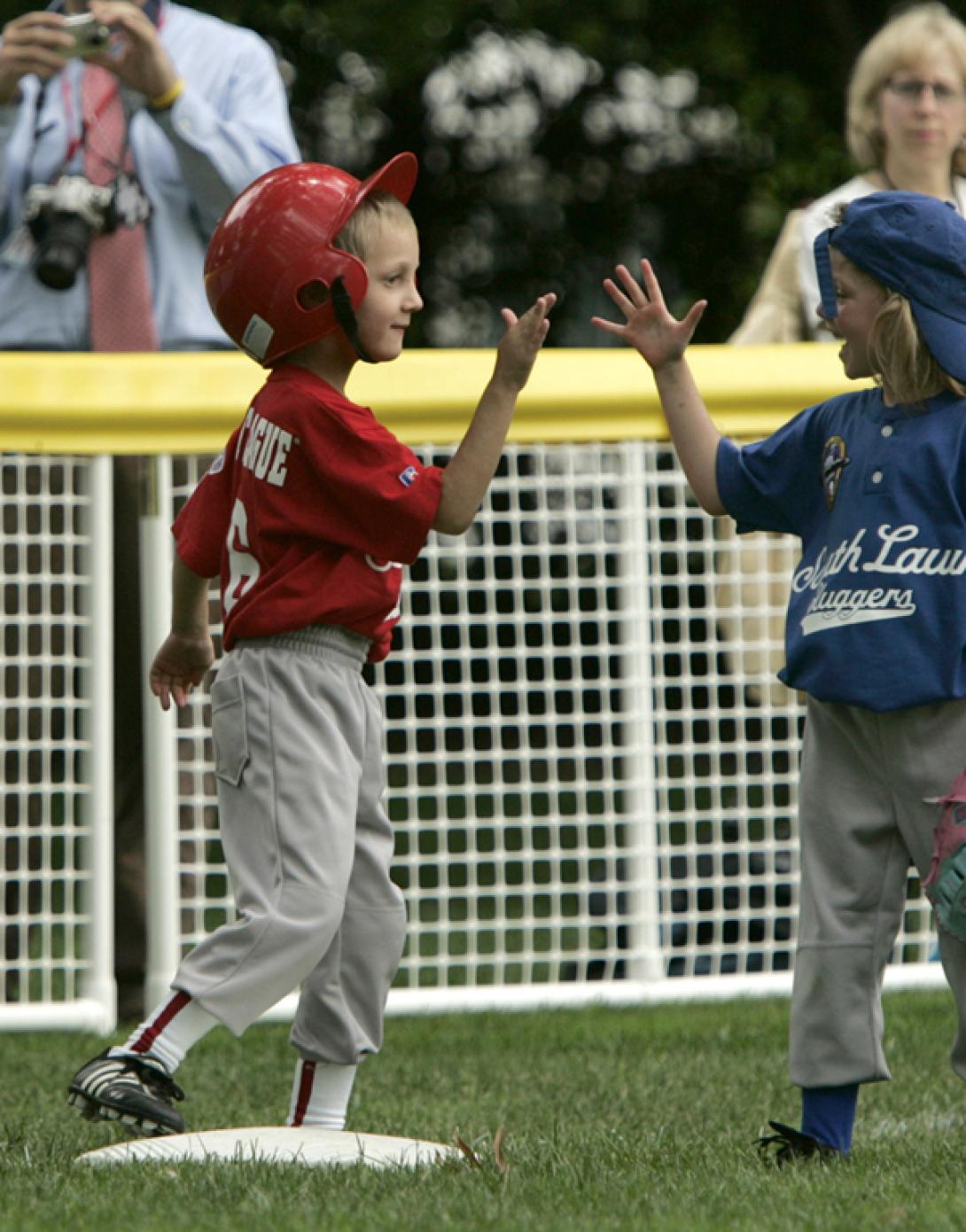 Two opposing players high-five on the field