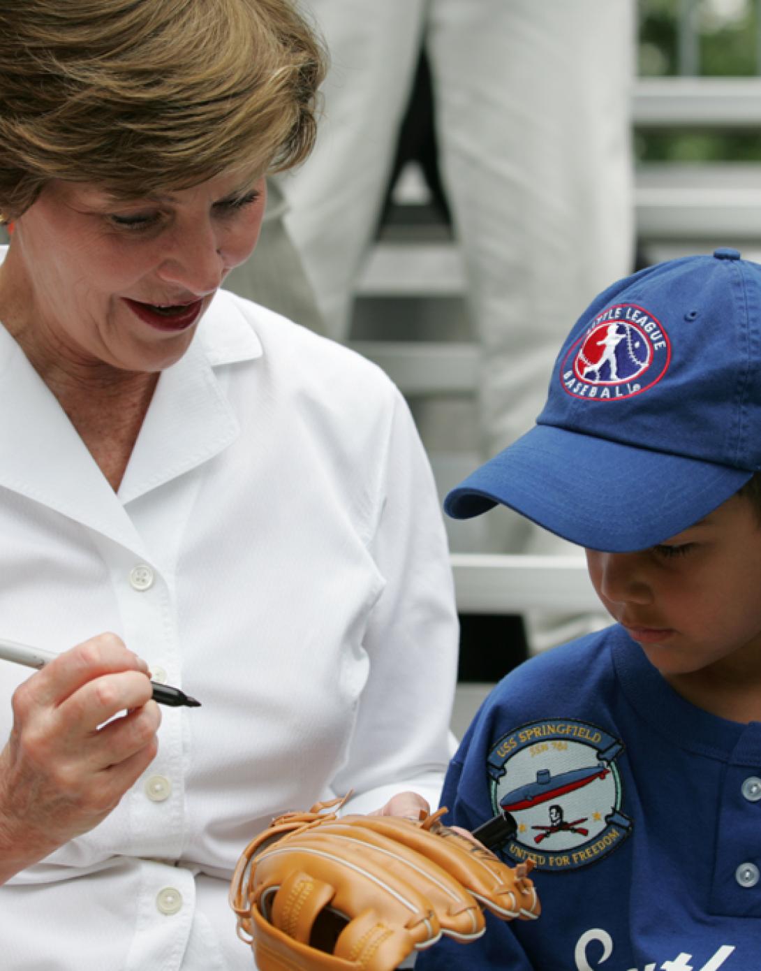 Mrs. Laura W. Bush autographs a glove for a Dolcom Little League Indian.