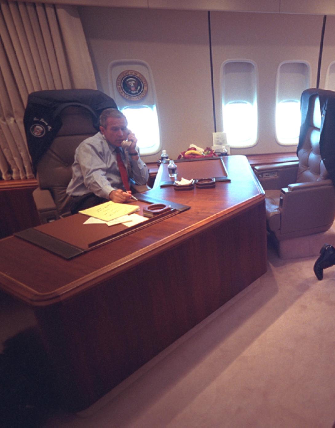 President George W. Bush talks on the telephone, September 11, 2001, as senior staff huddle aboard Air Force One. (P7079-10)
