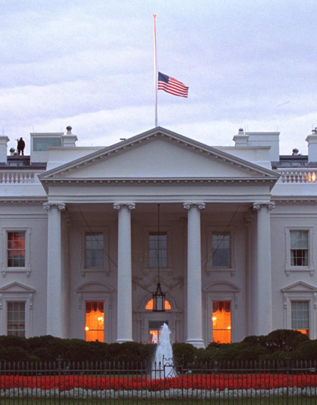 The American flag flies at half-staff over the White House at sunrise, September 14, 2001, as counter assault team (CAT) members are posted on the roof. (P7318-23)