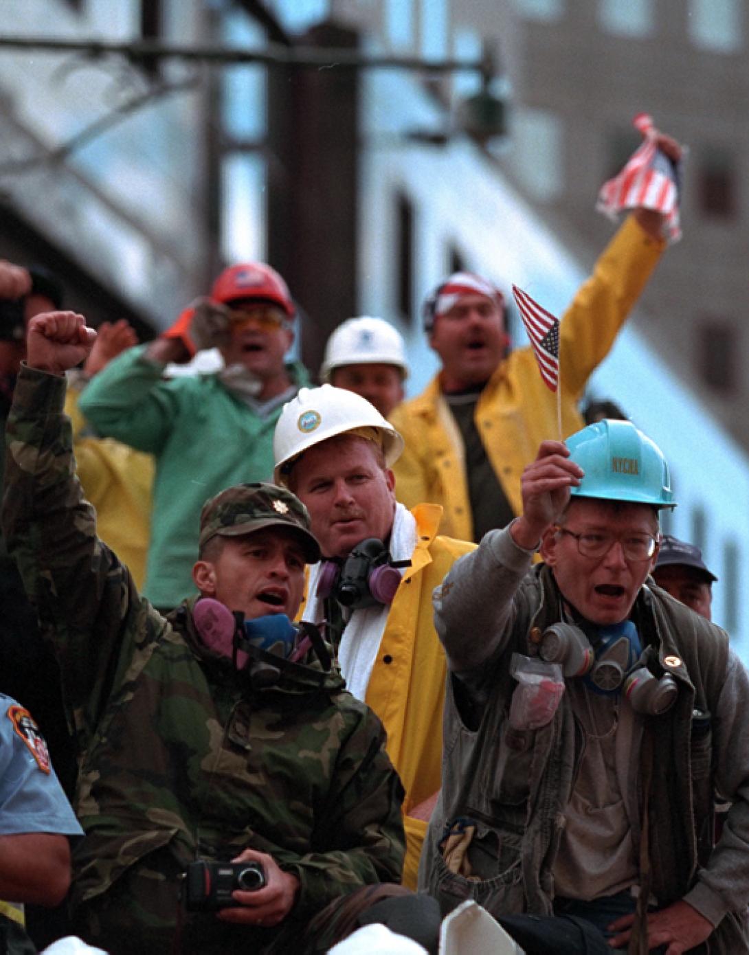 Rescue workers cheer, chant, and wave American flags as President Bush visits Ground Zero.