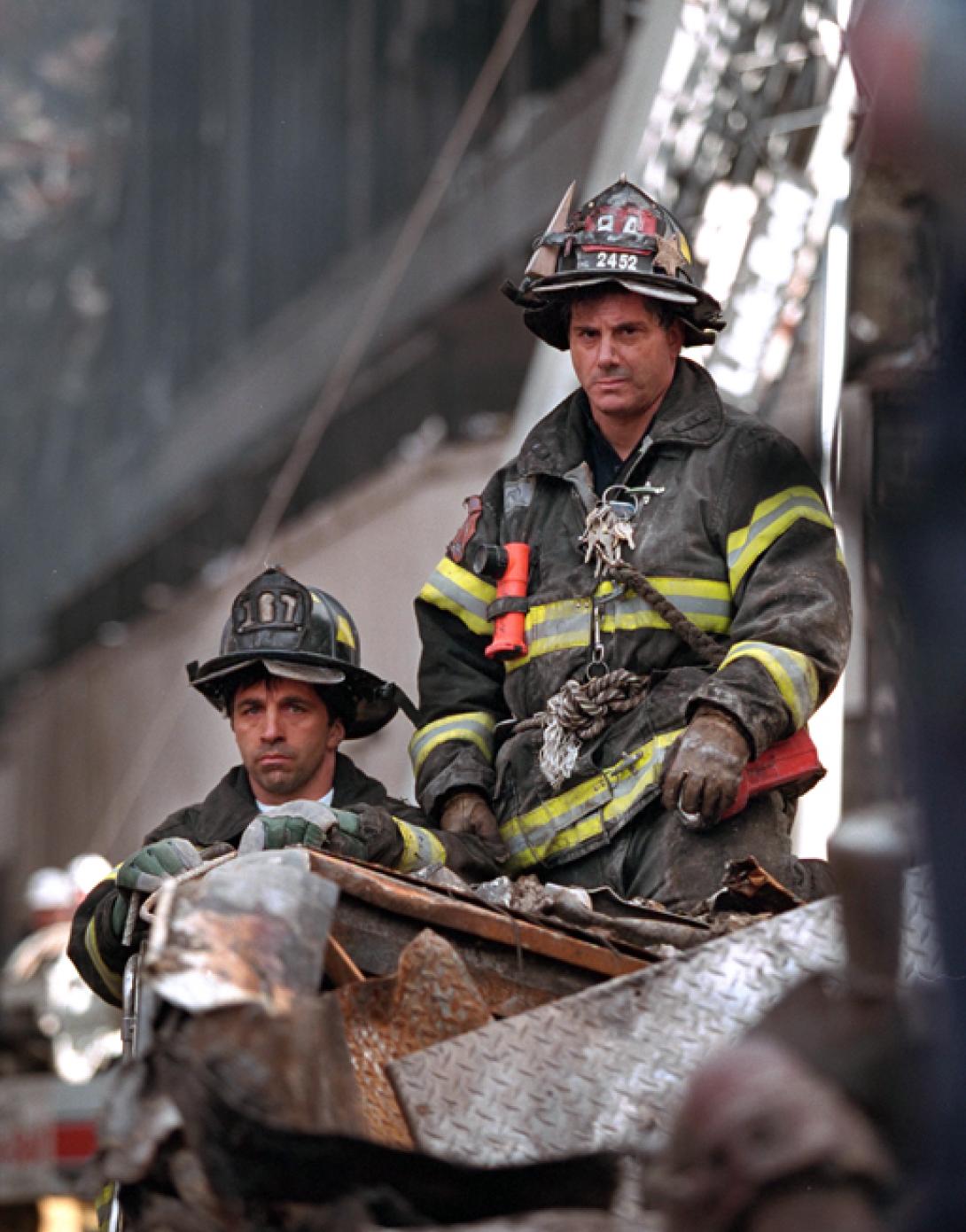 Two firefighters listen to President George W. Bush, September 14, 2001, during his visit to New York City and the site of the terrorist attacks on the World Trade Center. (P7377-06)
