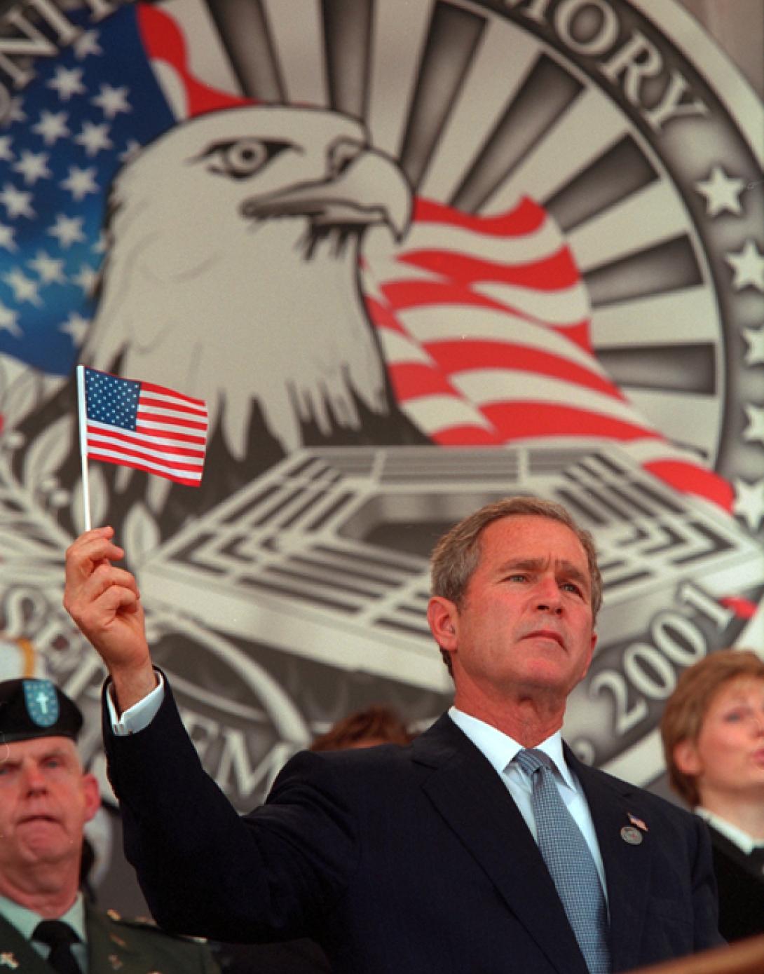 President George W. Bush holds up a small American flag, October 11, 2001, during the Department of Defense Service of Remembrance for those who lost their lives at the Pentagon on September 11th in Arlington, Virginia. (P8416-16)