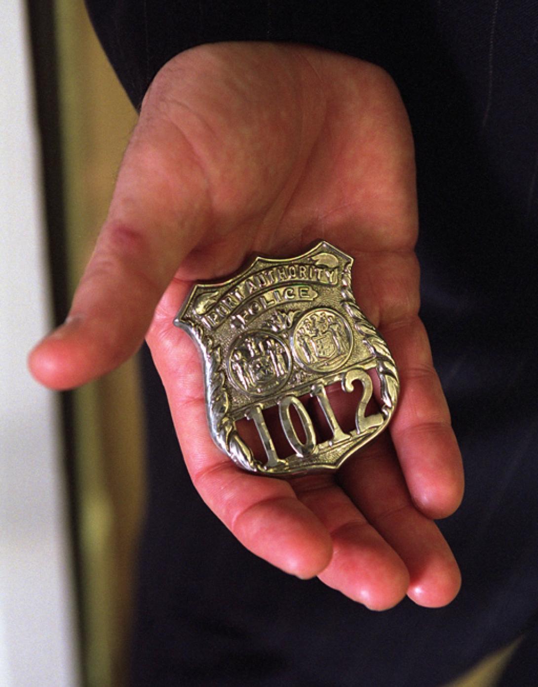Standing in the Oval Office, October 15, 2001, President George W. Bush holds the badge of a police officer killed in the September attacks. (P8576-12a)