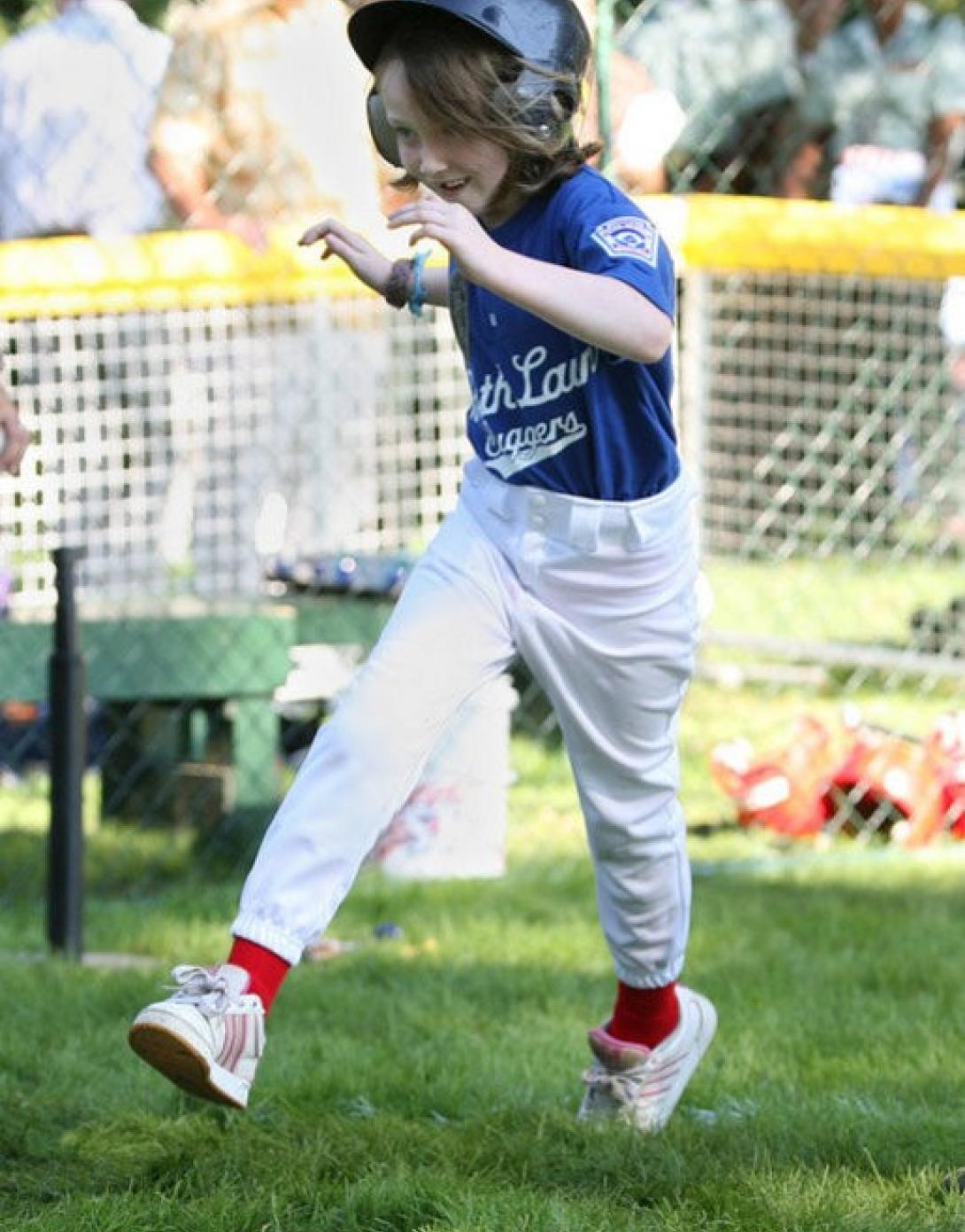 A tee ball player runs across home plate